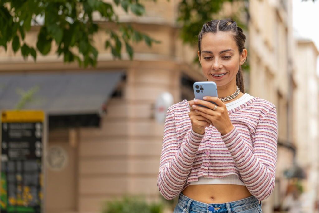 Mädchen mit fester Zahnspange schaut aufs Handy im Urlaub