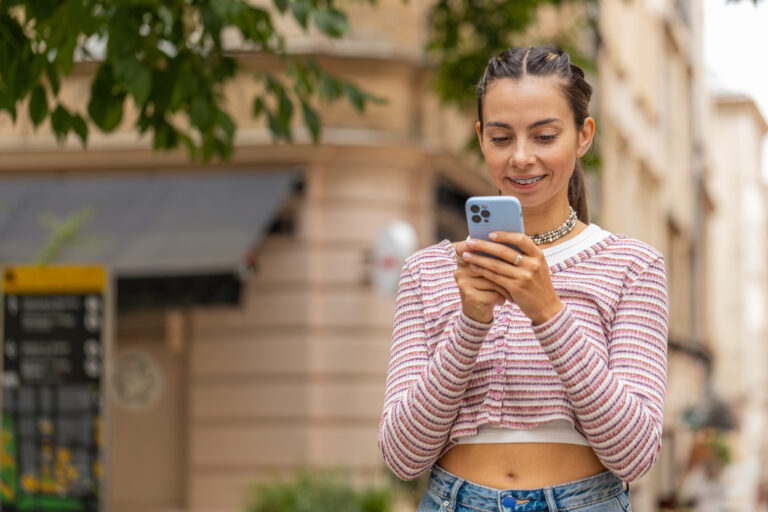 Mädchen mit fester Zahnspange schaut aufs Handy im Urlaub